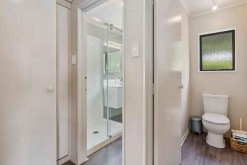 a bathroom with a toilet and a glass shower at Splendour on Spencer - Lake Tarawera Holiday Home in Lake Tarawera