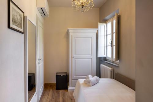 a bedroom with a white bed and a chandelier at B&B Ninfeo dell' Arancera in Calci