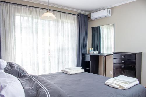 a bedroom with a bed and a dresser and a window at Inviting 3-Bed Apartment In The City in Umtali