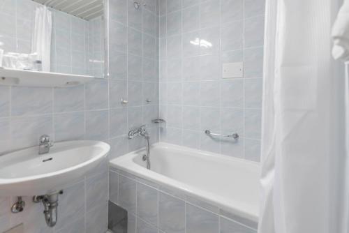 a white bathroom with a tub and a sink at Hotel Park in Čakovec