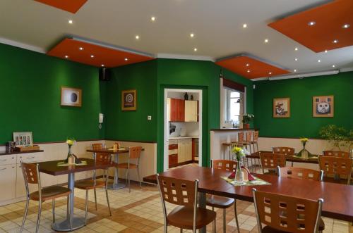 un comedor con paredes verdes, mesas y sillas en Residence Salvia, en Liberec
