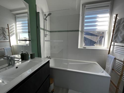 a white bathroom with a tub and a sink at Lostendro, appartements vue port in Le Guilvinec