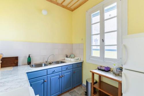 Una cocina con gabinetes azules y un refrigerador blanco. en Traditional house at Koroni near beach, en Koroni