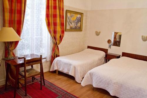 a bedroom with two beds and a table and a window at Hotel Cronstadt in Nice