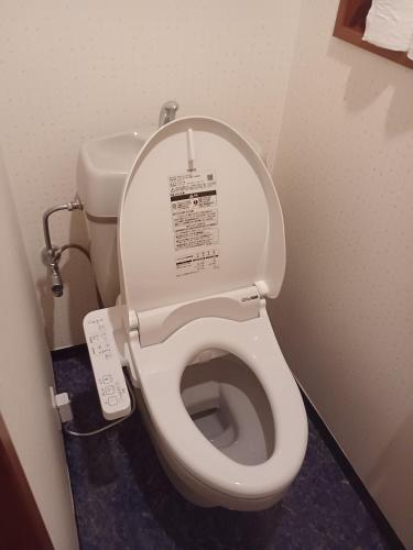a white toilet in a bathroom with a remote control at 白浜 Mizuki-ya in Kamitondacho