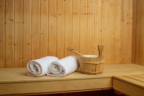 a sauna with two towels and a wooden bucket at Hotel-Restaurant Le Mont Paisible, Crans-Montana in Crans-Montana