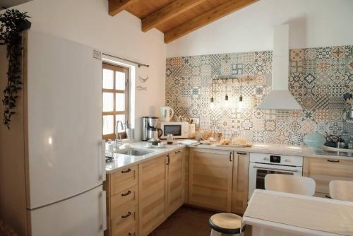 una cucina con armadi in legno e frigorifero bianco di Cosy Farmhouse Quinta da Eira 140 years old a Loulé