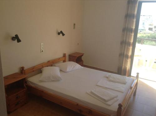 1 dormitorio con 1 cama con sábanas blancas y ventana en Studio Stella, en Plakias
