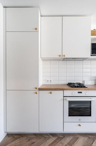 a white kitchen with white cabinets and a stove at Butas nuomai Šiauliuose in Šiauliai