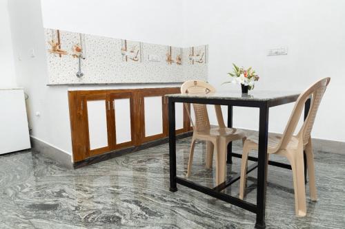 a kitchen with a black table and two chairs at BrightMoon_Homestay in Pondicherry