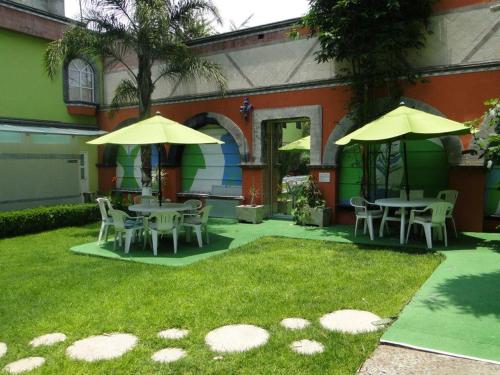 a patio with tables and umbrellas on the grass at Hotel Cuellar in Tula de Allende