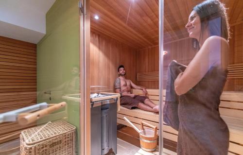 a man in a sauna with a woman sitting in a tub at Hotel juenmi in Sillian