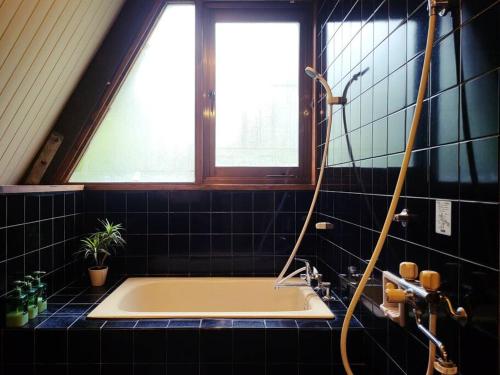a bathroom with a bath tub with a window at LOGIN OKINAWA -plants- in Onna