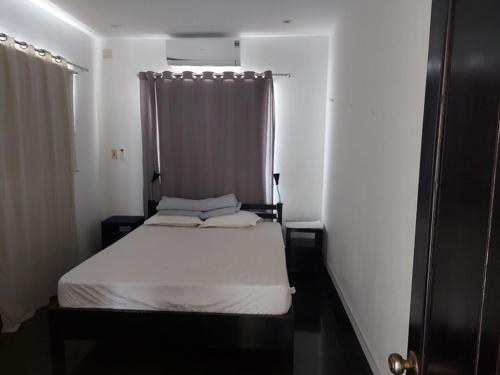 a small bedroom with a white bed and a window at La Maison Ganh Do in Phu Yen