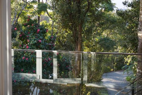 a view of a fence with a garden with roses at Torbay Tree Tops in Auckland