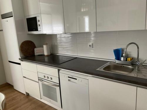 a kitchen with white cabinets and a sink and a counter at Apartamento pacifico a in Madrid
