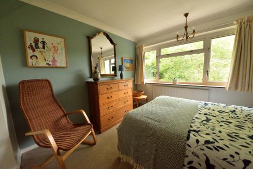 a bedroom with a bed and a chair and a mirror at Cosy house, a train spotter's delight! in New Alresford