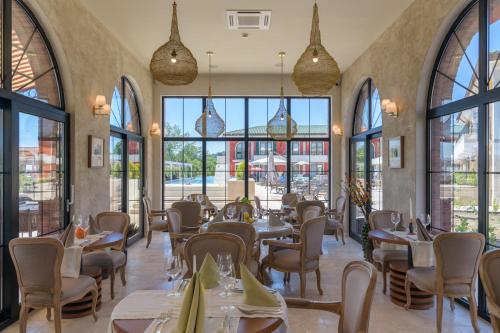 un restaurante con mesas, sillas y ventanas grandes en Villas for 4 or 6 Adults in Therma Village - Private Beach & Free Parking en Kranevo