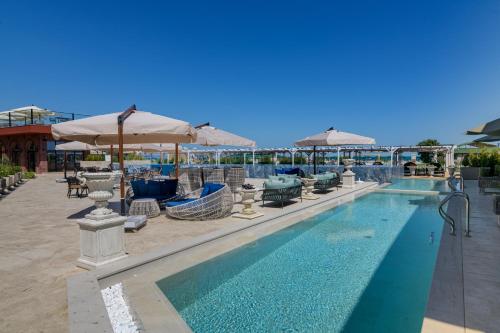 a swimming pool with tables and chairs and umbrellas at Luxury Villas in Therma Village - Mineral Pool & SPA in Kranevo