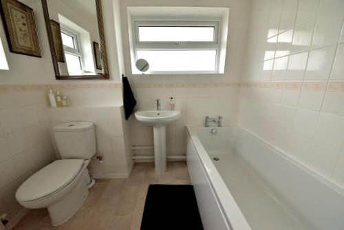 a bathroom with a toilet and a sink and a tub at Cosy house, a train spotter's delight! in New Alresford