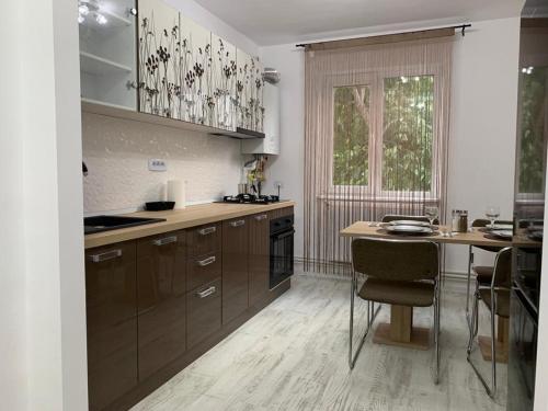 a kitchen with brown cabinets and a table with chairs at Central Alexa Apartament in Bacău