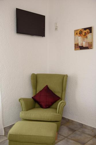 a living room with a green chair and a television at Lakki Village in Aegiali