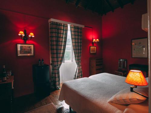 a bedroom with red walls and a bed and a window at Hotel Rural La Casa Amarilla in Los Silos