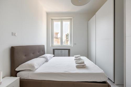 a bedroom with a bed with white sheets and a window at Garibaldi & Gae Aulenti Modern Apt with Private Parking! in Milan