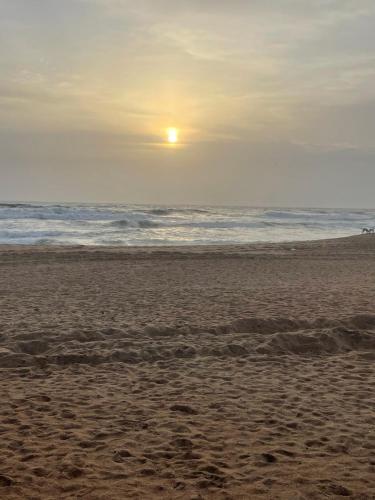 a beach with the sun rising over the ocean at Baga View Inn in Baga