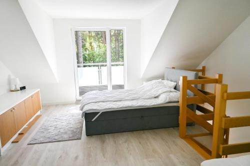 biała sypialnia z łóżkiem i schodami w obiekcie Komfortowy apartament dwupoziomowy w cichej okolicy w Pobierowie