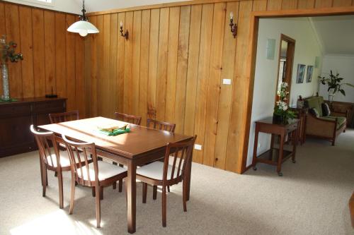 comedor con mesa de madera y sillas en Ahstyk Cottage, en Burnt Pine