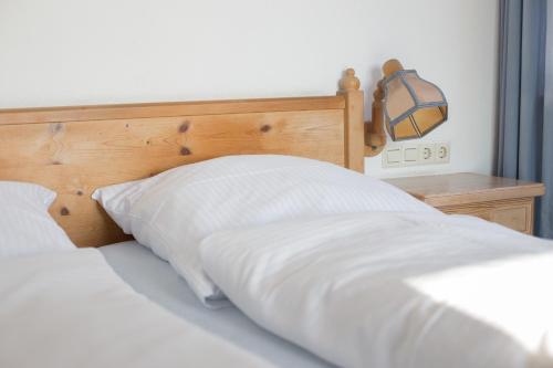 a bed with white sheets and a wooden headboard at Landgasthof Bieg in Neuler