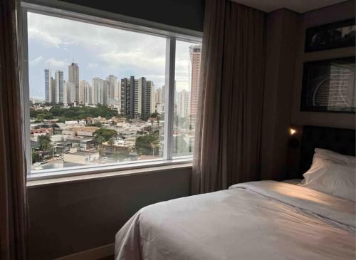 a bedroom with a view of a city from a window at QS Marista - Studio Alessandra Antonelli - Flat 1708 in Goiânia