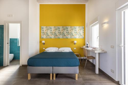 a bedroom with a bed and a yellow wall at I Gelsomini Guest House in Noto