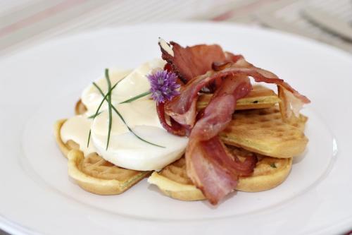 a white plate with waffles with bacon and cheese at L'abri Bed and Breakfast in Akaroa