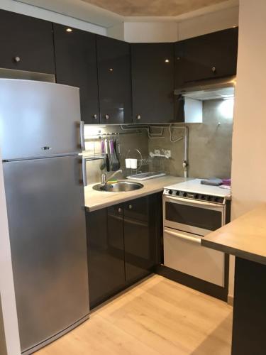 a kitchen with black cabinets and a stainless steel refrigerator at Le Barcares in Le Barcarès