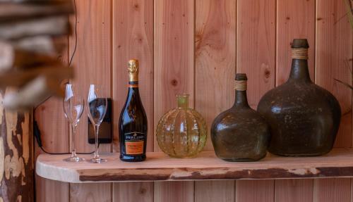 three bottles of wine sitting on a shelf with wine glasses at LAC ABANE AU LAC in Butgenbach