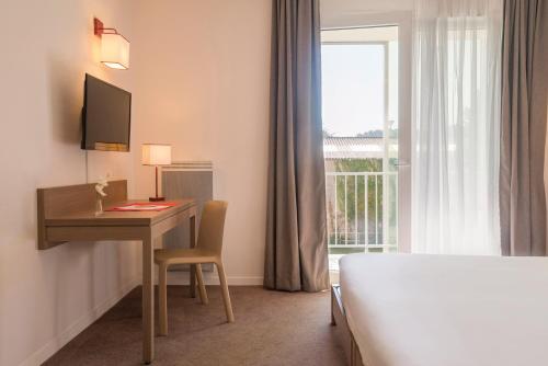 シェルブール・アン・コタンタンにあるAppart'City Confort Cherbourgのデスク、ベッド、窓が備わるホテルルームです。