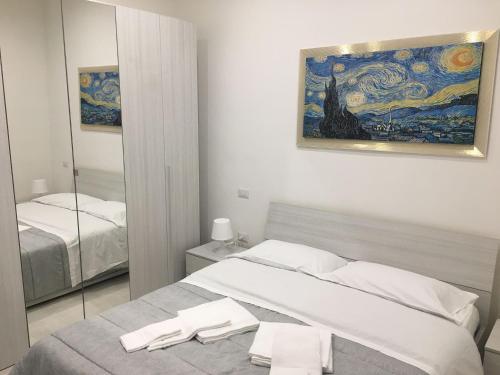 a white bedroom with a bed and a mirror at InBlu in Bari