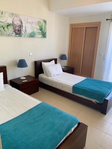 a bedroom with two beds and a painting on the wall at Apartamento Nectarina - Cabanas Beach Clube in Cabanas de Tavira