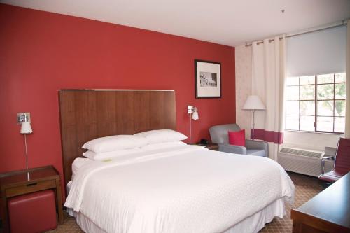a bedroom with a white bed and a red wall at La Hacienda San Jose Silicon Valley in San Jose