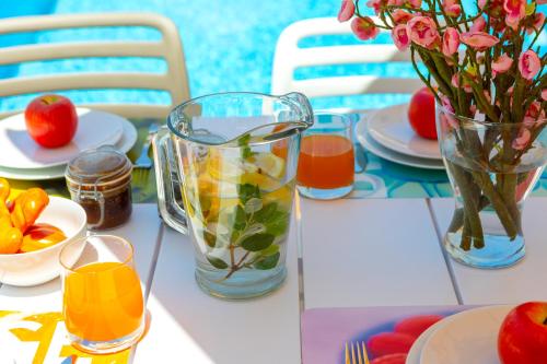 a table with a vase of flowers and fruit on it at Villa Lantos Central Protaras in Protaras