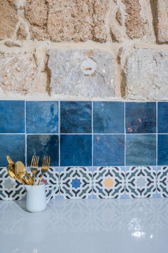 a kitchen counter with blue and white tile on a wall at Jozefin in ‘Akko