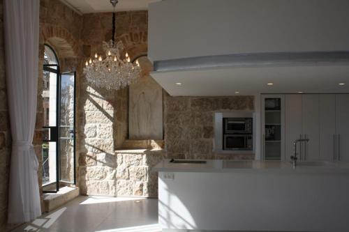 a kitchen with a chandelier hanging over a counter at The White House Jerusalem סוויטת הבית הלבן ירושלים in Jerusalem