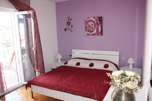 Un dormitorio con una cama roja y un jarrón de flores en Lorena with sea view, en Rovinj