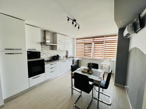 a kitchen with white cabinets and a table with chairs at Denis Apartament in Turda