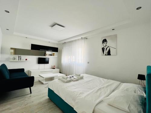 a white bedroom with a bed and a couch at Denis Apartament in Turda
