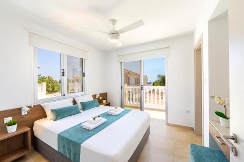 a bedroom with a large white bed and large windows at Villa Lantos Central Protaras in Protaras