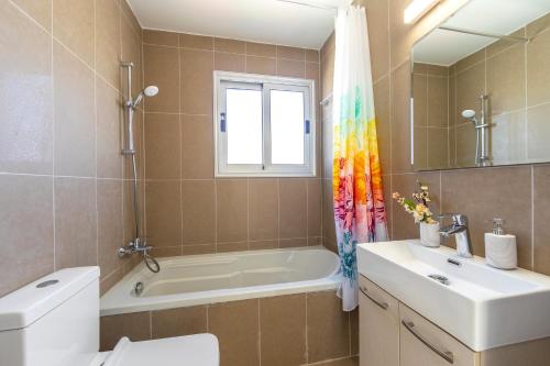 a bathroom with a tub and a toilet and a sink at Villa Lantos Central Protaras in Protaras