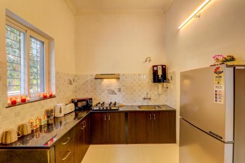 a kitchen with wooden cabinets and a refrigerator at Ludo Private Pool Villa, WiFi-Caretaker-Parking, North Goa in Baga